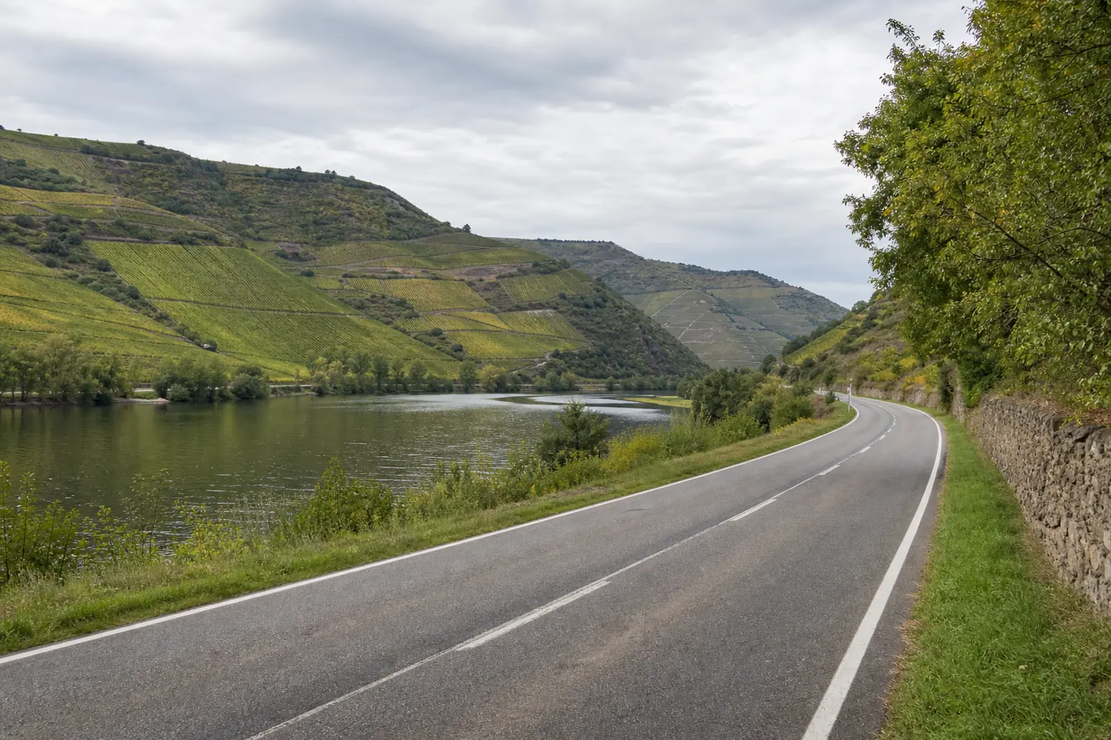 Landstra&szlig;e entlang eines breiten Flusstals mit bewachsenen H&ouml;henz&uuml;gen im Hintergrund